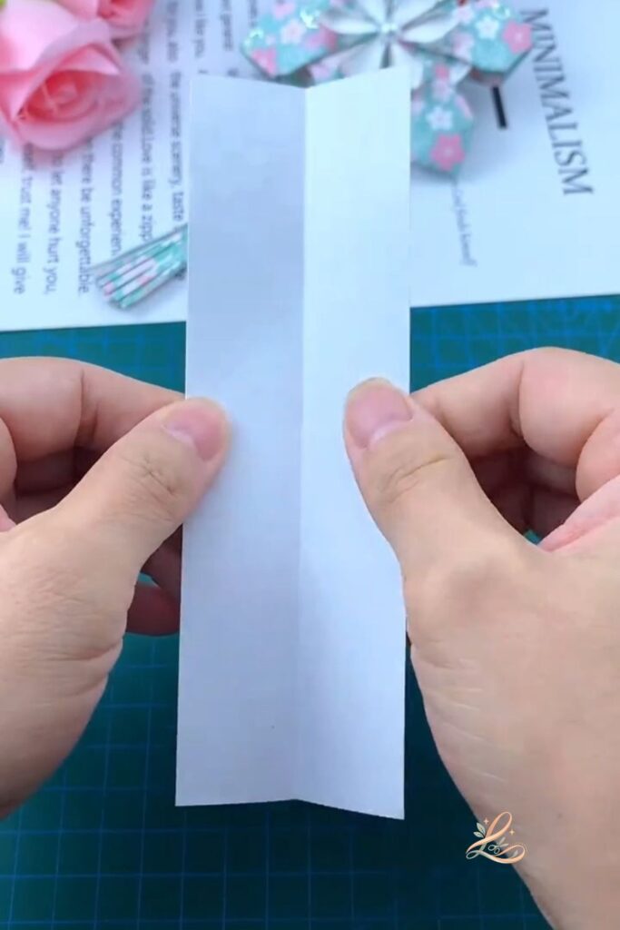 The pink patterned paper strip held upright in both hands