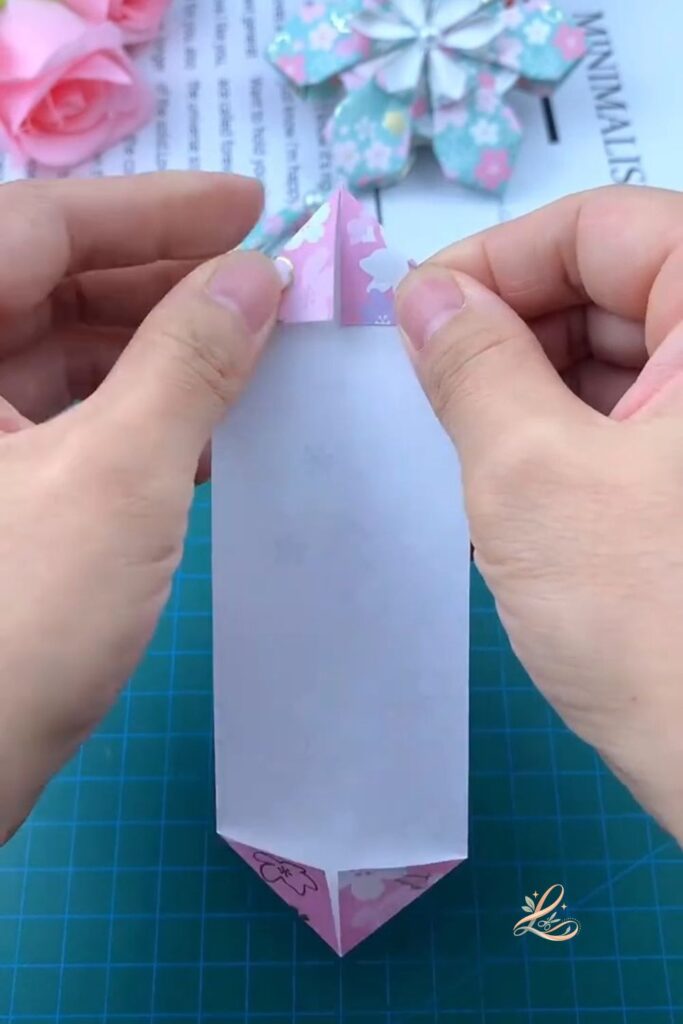 The module held up to show both the top and bottom diamond points, all four corner folds pressed flat, the full double-pointed shape clearly visible against the background