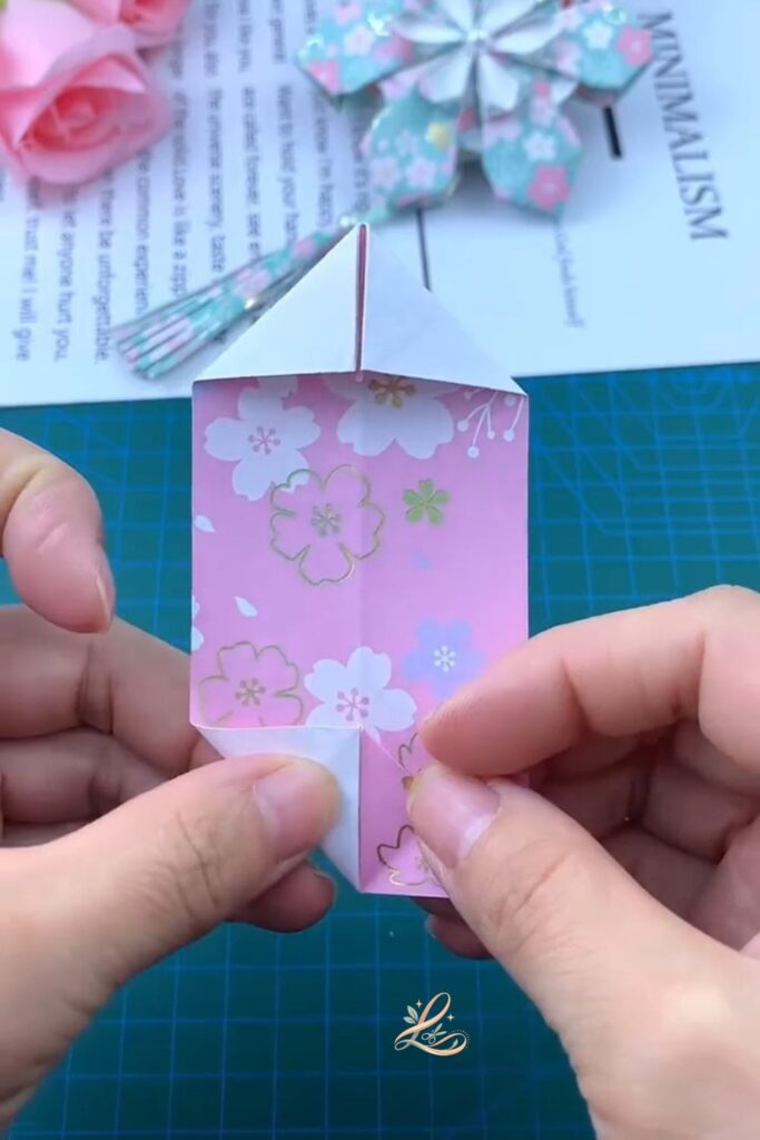 The fully opened 3D petal module held in one palm, clearly showing the puffed-out 3D shape, patterned paper on the outside, the box-like structure visible from slightly above