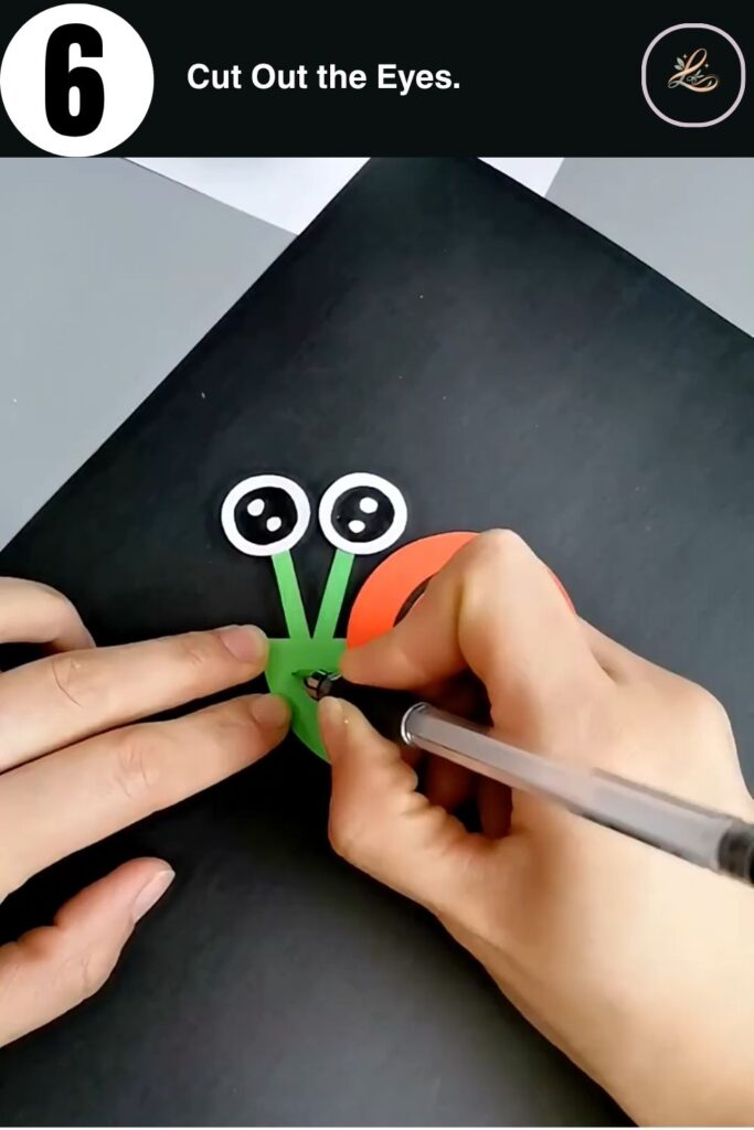 Cute paper snail with white kawaii eyes on green antennae strips held in hands during assembly