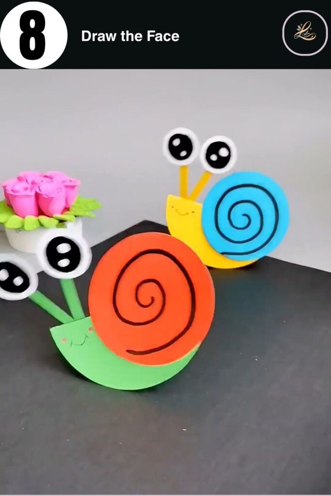 Finished DIY paper snail craft with kawaii face and spiral shell standing on a dark surface