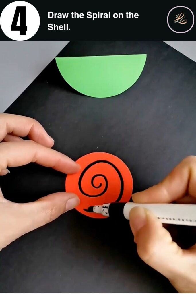 Drawing a black spiral on an orange paper circle to create a snail shell for a DIY paper craft