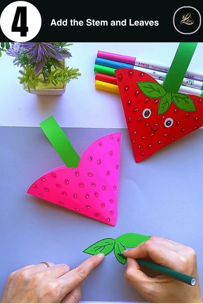 Attaching a green paper leaf and stem to the top of a 3D paper strawberry.