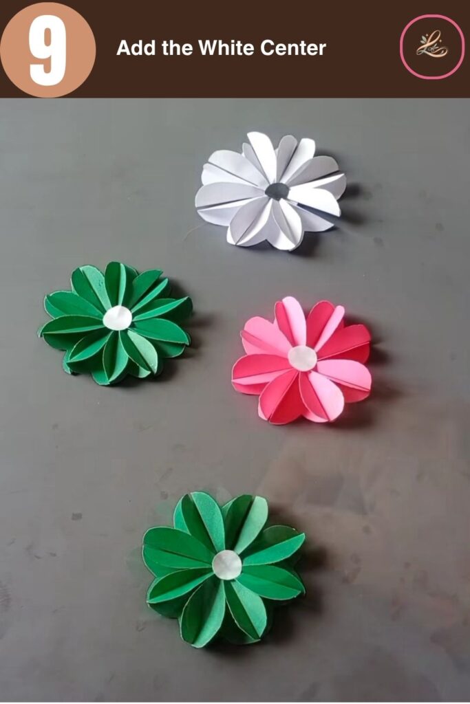 Pretty Paper Daisy Flower Craft for Kids A finished green paper daisy flower featuring a white circular center emblem on a gray background.