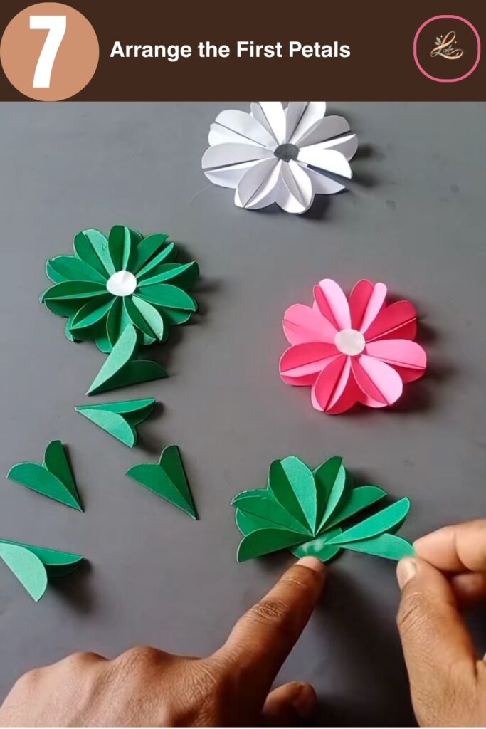 Pretty Paper Daisy Flower Craft for Kids Placing pointed green paper petals onto a glued circular base to form the first half of a flower.
