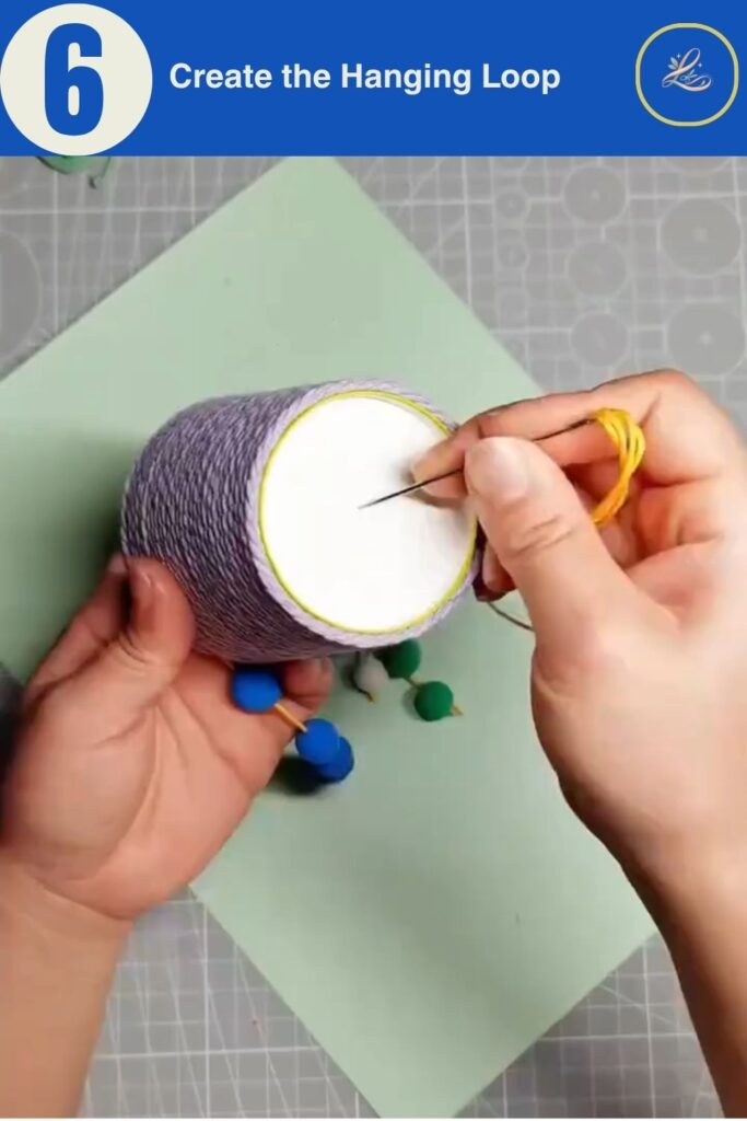 Colorful Cup Wind Chime Mobile for Beginners (DIY Decor) Pulling a top hanging string through a finished yarn-covered cup.