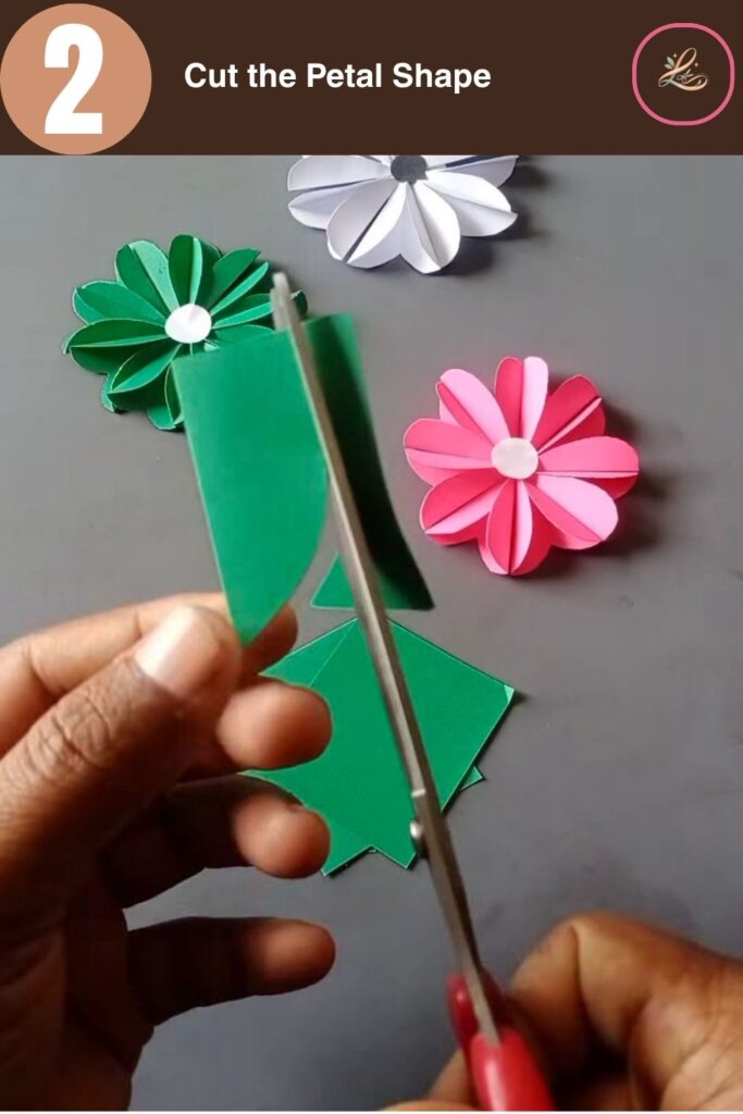 Pretty Paper Daisy Flower Craft for Kids Cutting a curved petal shape into folded green paper using silver craft scissors.