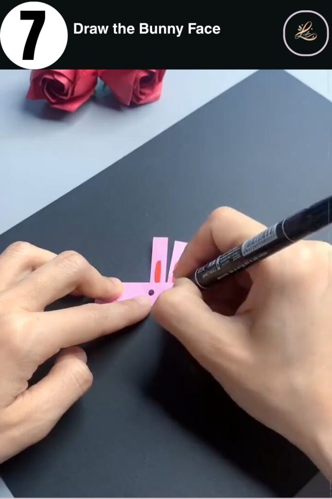 Drawing a kawaii bunny face on a paper finger ring with a black marker
