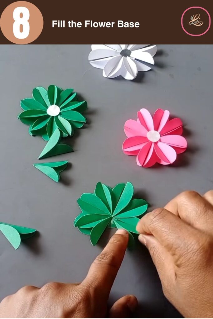 Pretty Paper Daisy Flower Craft for Kids Fitting the last pointed green paper petal onto the base to form a complete circular flower design.