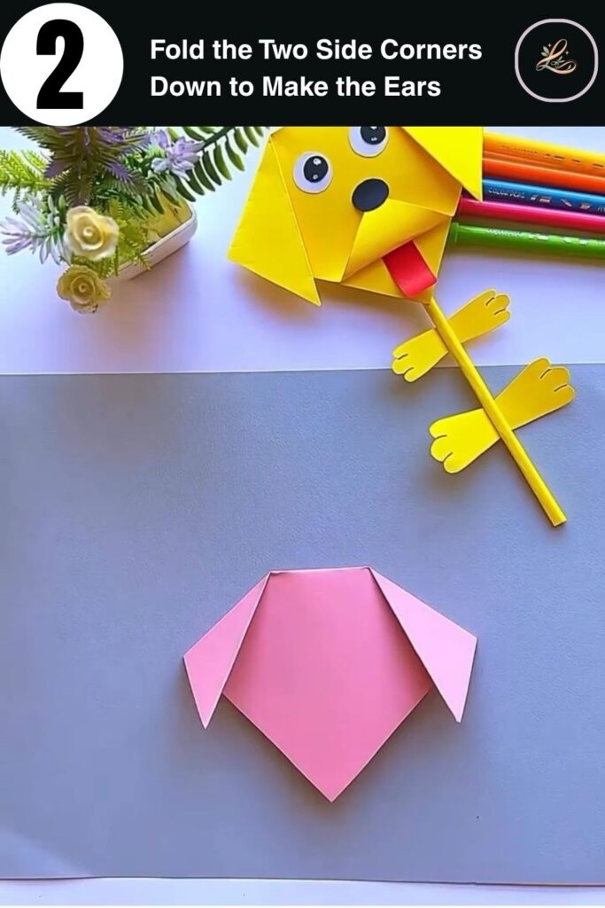 Pink cardstock folded with two ear flaps to form a paper dog face shape for a pencil topper craft