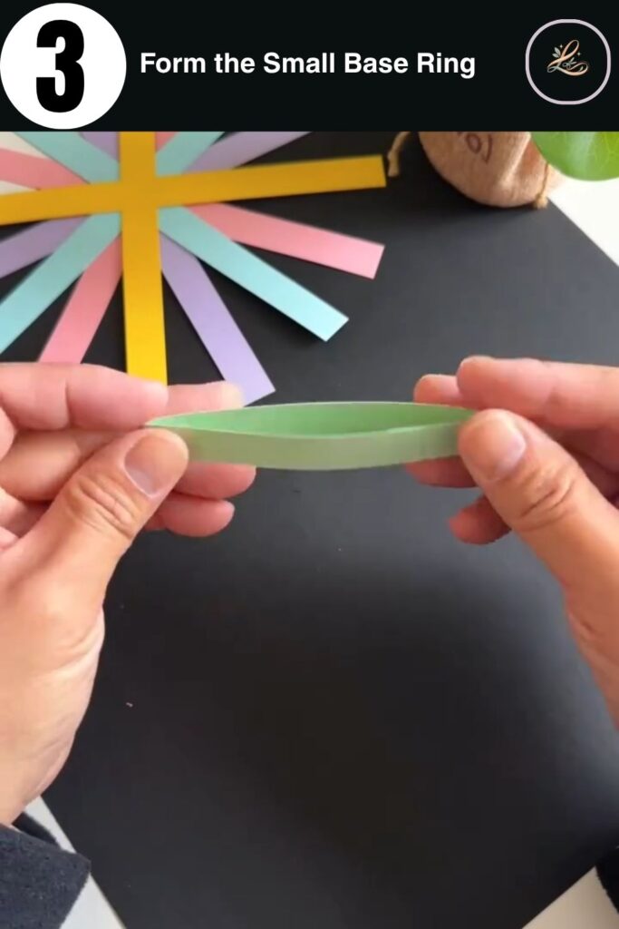 Small mint green paper ring formed from a strip as part of a DIY paper bag craft for kids, held up to show its circular shape