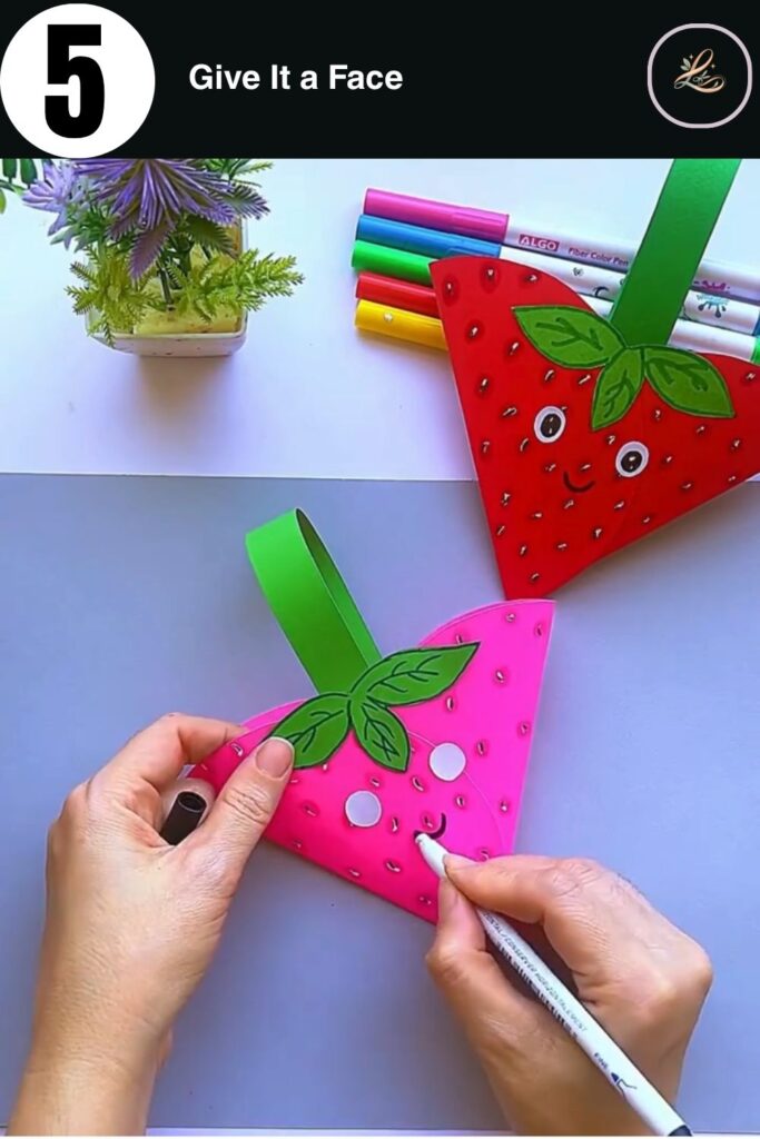 Drawing a cute kawaii face on a 3D paper strawberry.