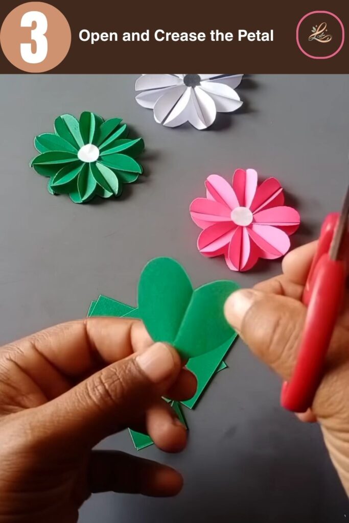 Pretty Paper Daisy Flower Craft for Kids An open green heart-shaped paper petal held up against a gray workspace background.