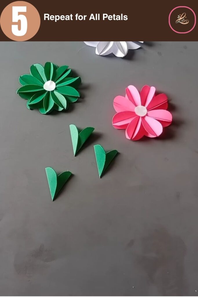Pretty Paper Daisy Flower Craft for Kids Multiple folded green paper flower petals spread across a gray crafting table.
