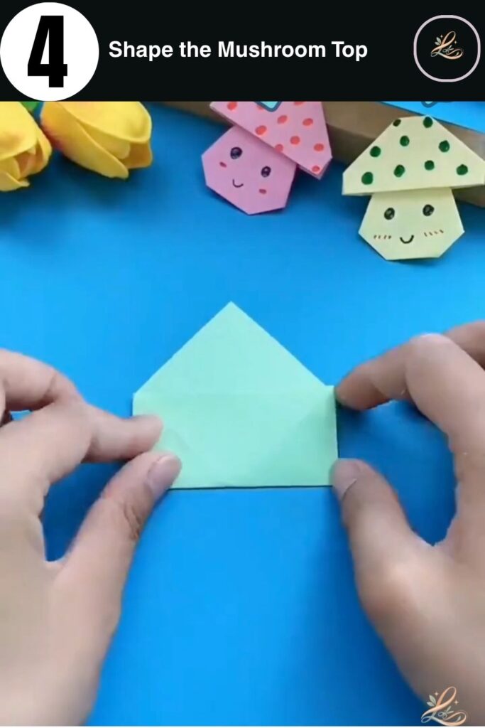 Folding the top corners of the paper down to create a triangle cap.