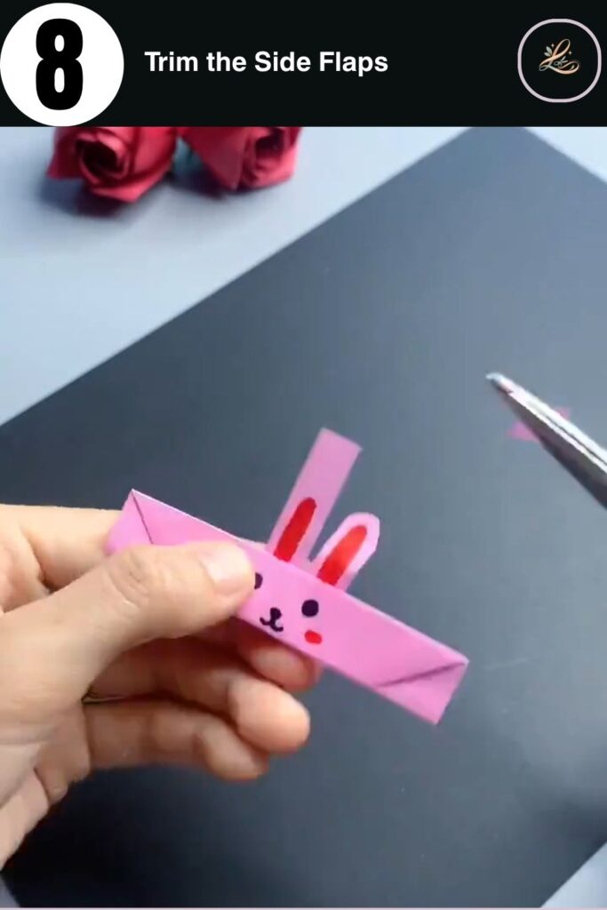 Trimming the side flaps of a paper bunny finger ring with scissors to finish the craft