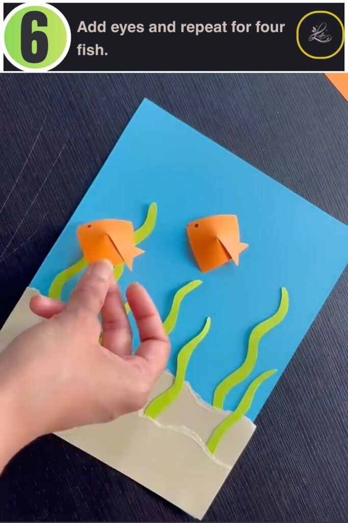 Four orange origami fish glued onto a paper ocean scene