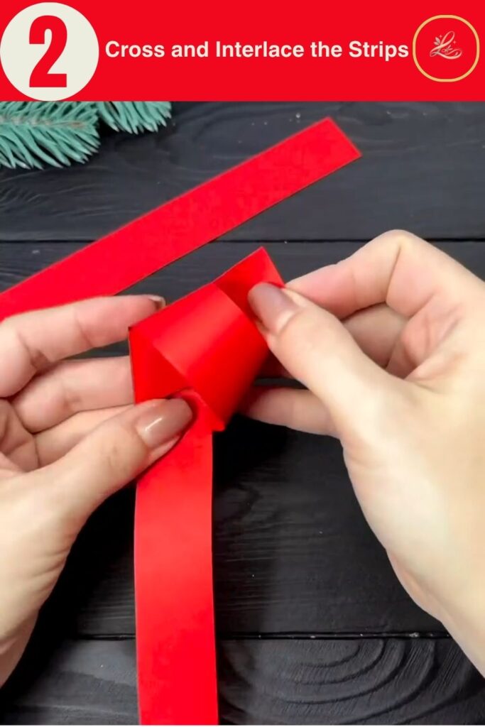 Hands crossing two red paper strips to form the base of a DIY paper star Christmas ornament