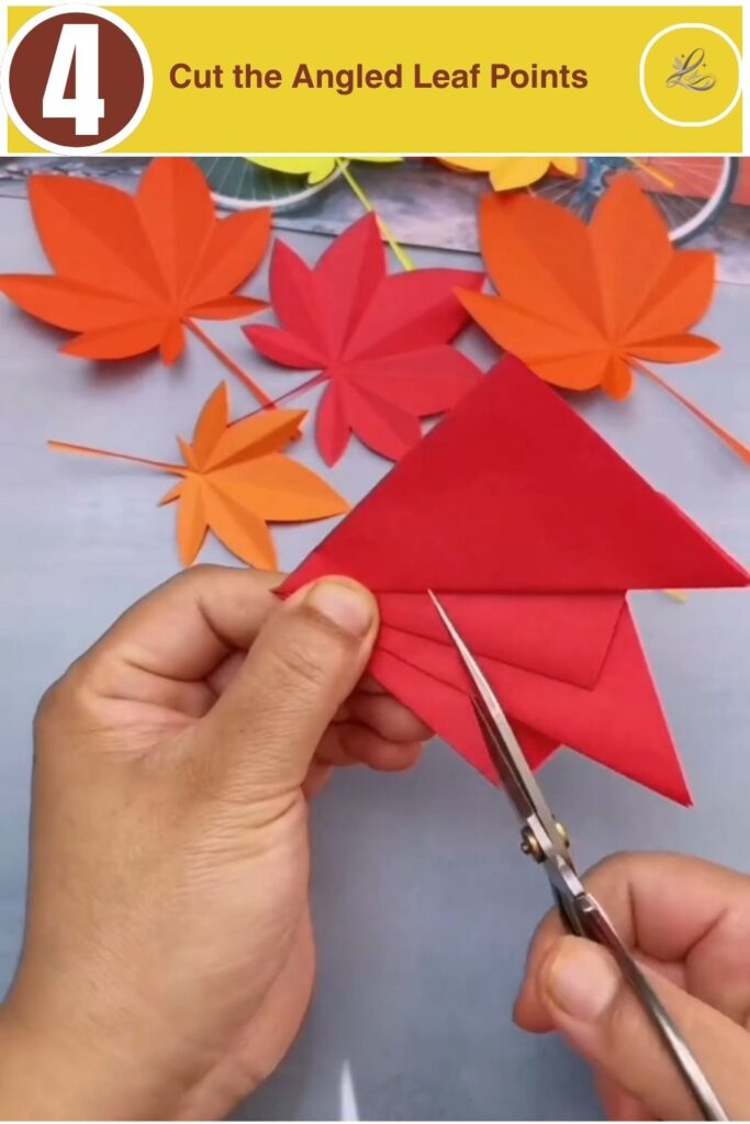 Scissors trimming the top edge of pleated red paper at a sharp angle.