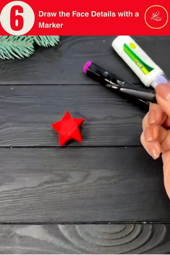 Drawing a face on a red paper star Christmas ornament with a black marker, festive DIY craft tutorial