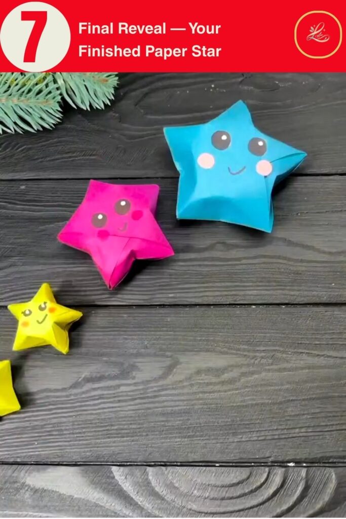 Finished DIY red paper star Christmas ornament with a drawn face, held up against a dark wood background with pine branch