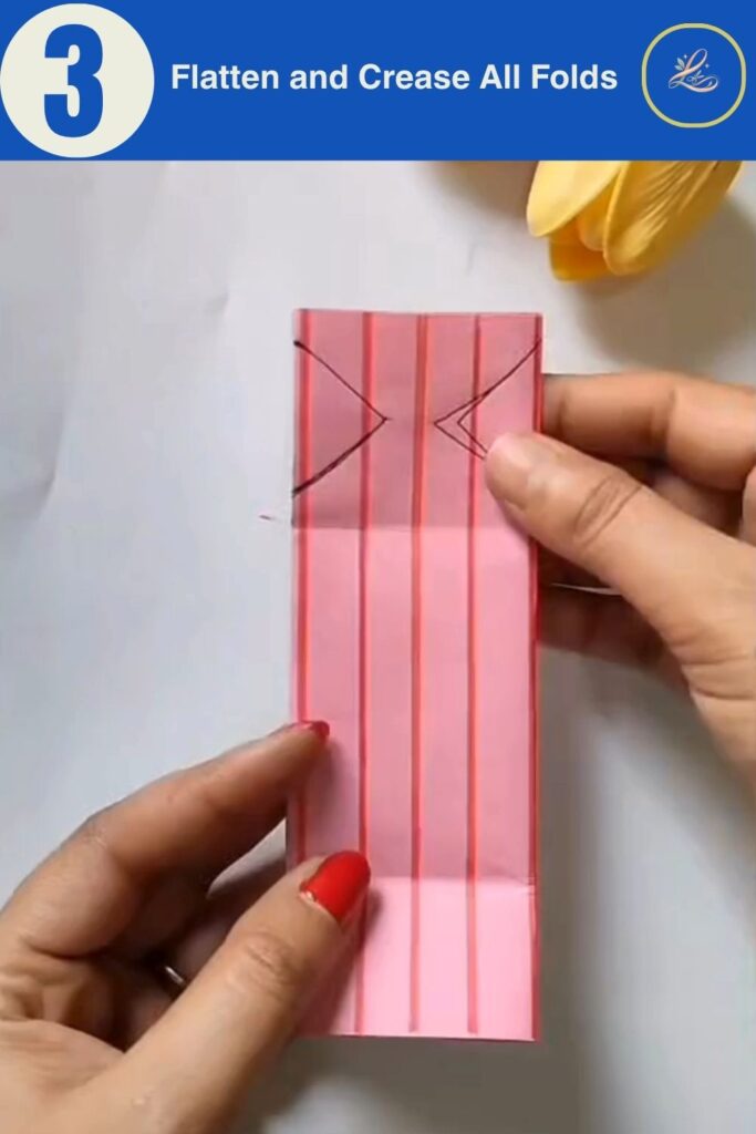 Hands flattening and creasing accordion-folded pink paper for a handmade birthday paper gift bag