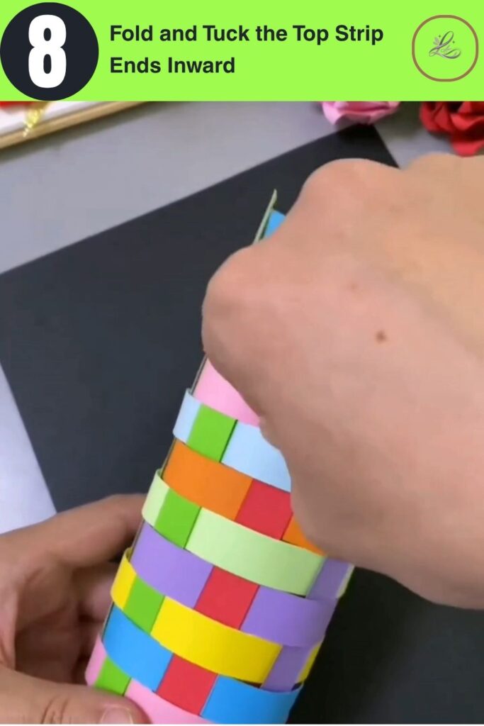Fun Rainbow Woven Paper Pencil Holder DIY (#1) Hands folding a paper strip tip inward over the top rim of a colorful woven paper pencil holder no-glue finishing technique