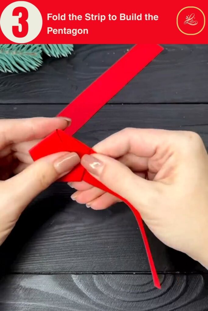 Hands folding red paper strips into a flat pentagon shape, the base structure of a DIY paper star ornament