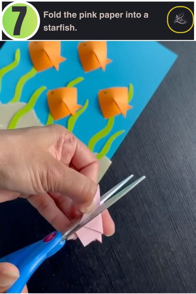 Pink cardstock folded and cut into a starfish shape for a paper ocean craft