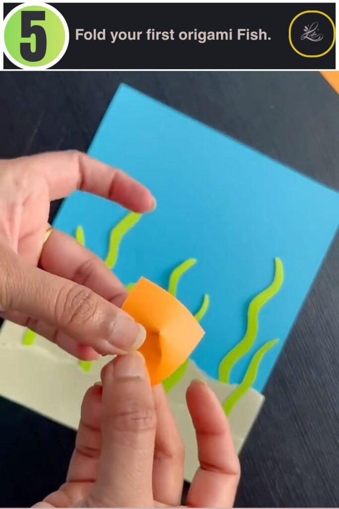 Orange cardstock being folded into an origami fish shape