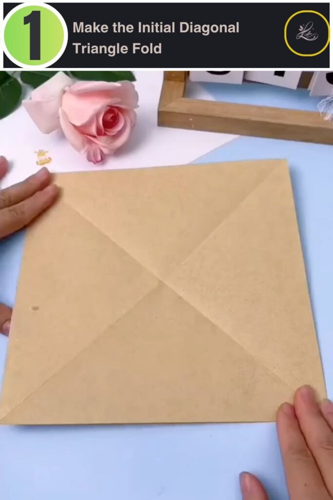 Folding a square piece of craft paper diagonally into a triangle.