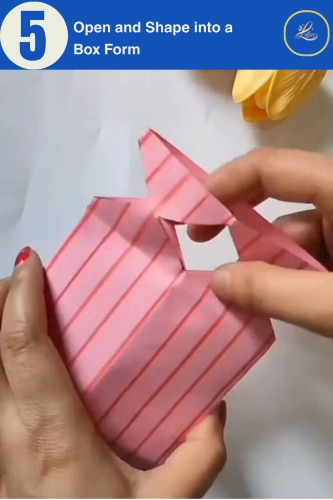 Hands opening accordion-folded pink paper into a 3D gift bag shape for a birthday paper craft DIY