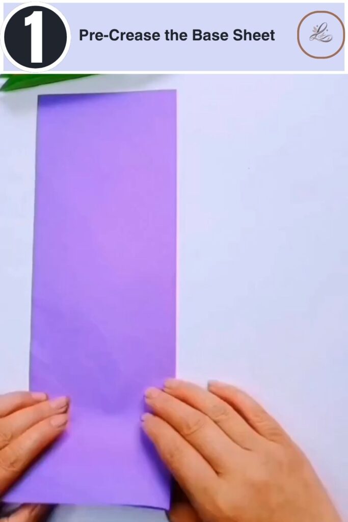 Colorful Paper Peacock Craft Anyone Can Make A person folding a purple rectangular piece of paper in half on a white background.