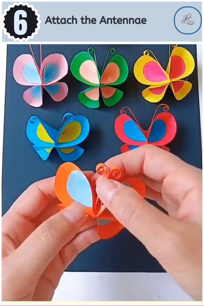 Attaching the curled paper antennae to the center of the paper wings.