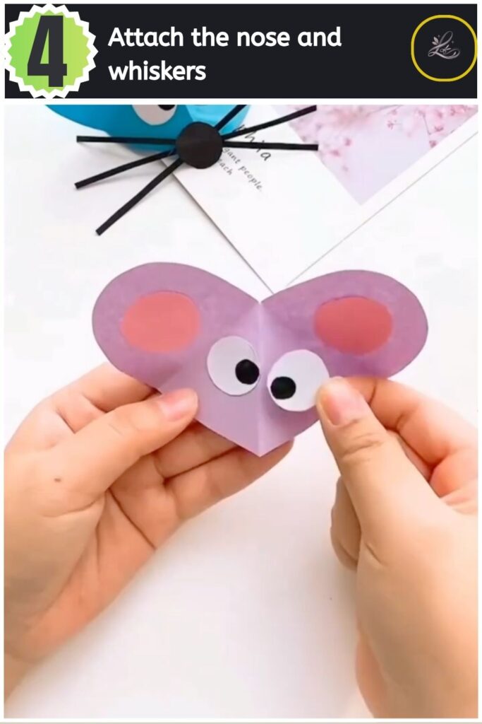 Adorable Paper Mouse Craft For Beginners Securing a black paper nose with whiskers to the paper mouse face.
