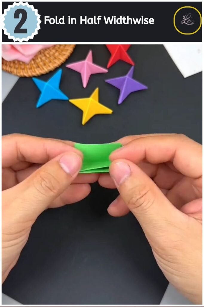 Folding a green paper strip in half widthwise to create a central guideline crease.