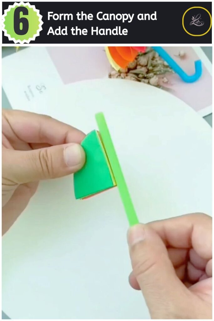 Inserting a green straw handle into the finished paper umbrella canopy.