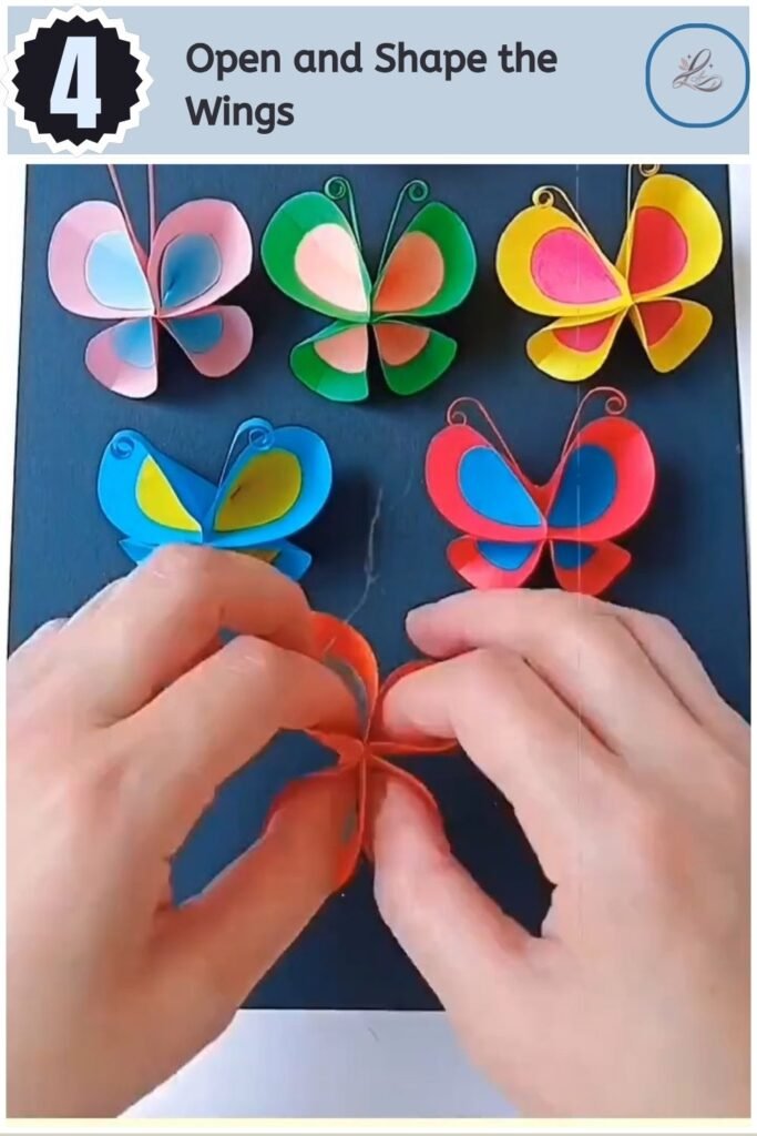 Hands opening the folded paper to display a completed 3D butterfly wing shape.