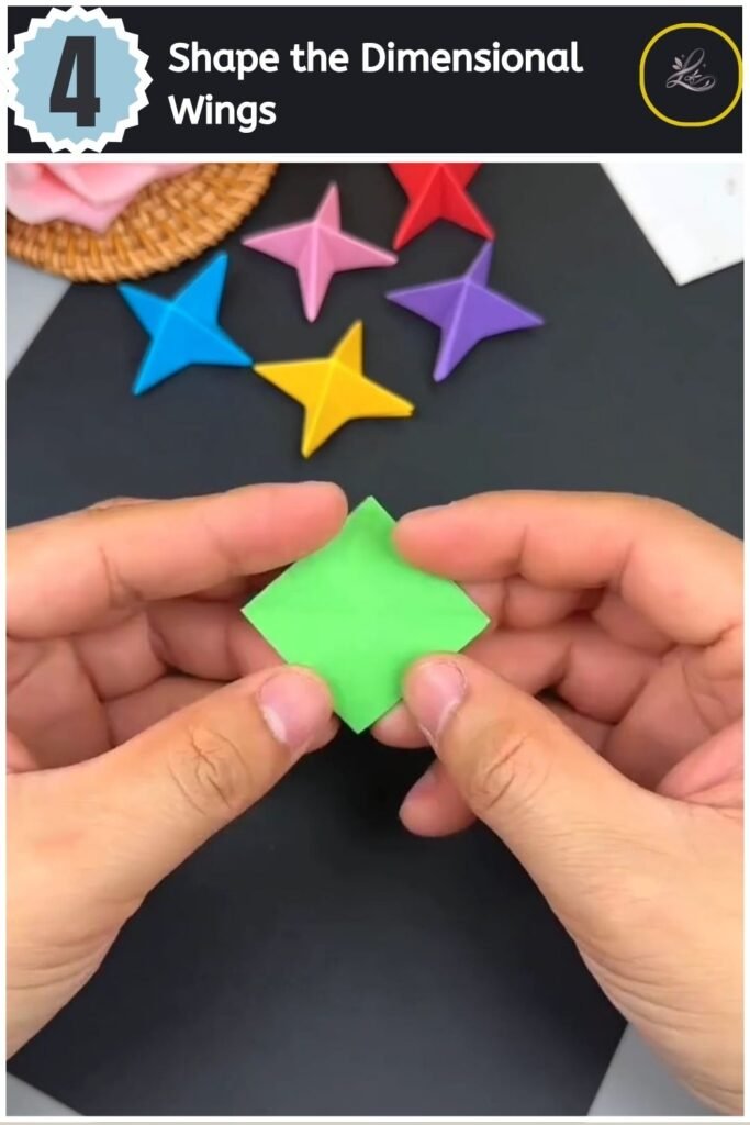 A finished green four-pointed 3D paper star held up against a black background.
