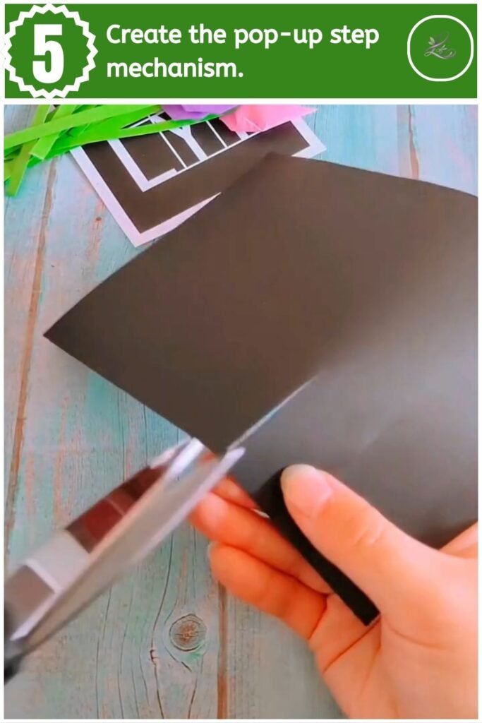 Making two cuts along the folded crease of black cardstock to form a pop-up tab.
