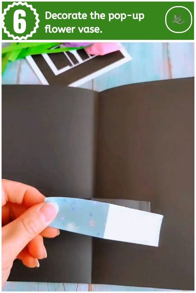 Glueing a blue patterned paper strip across the pop-up mechanism inside a black card.