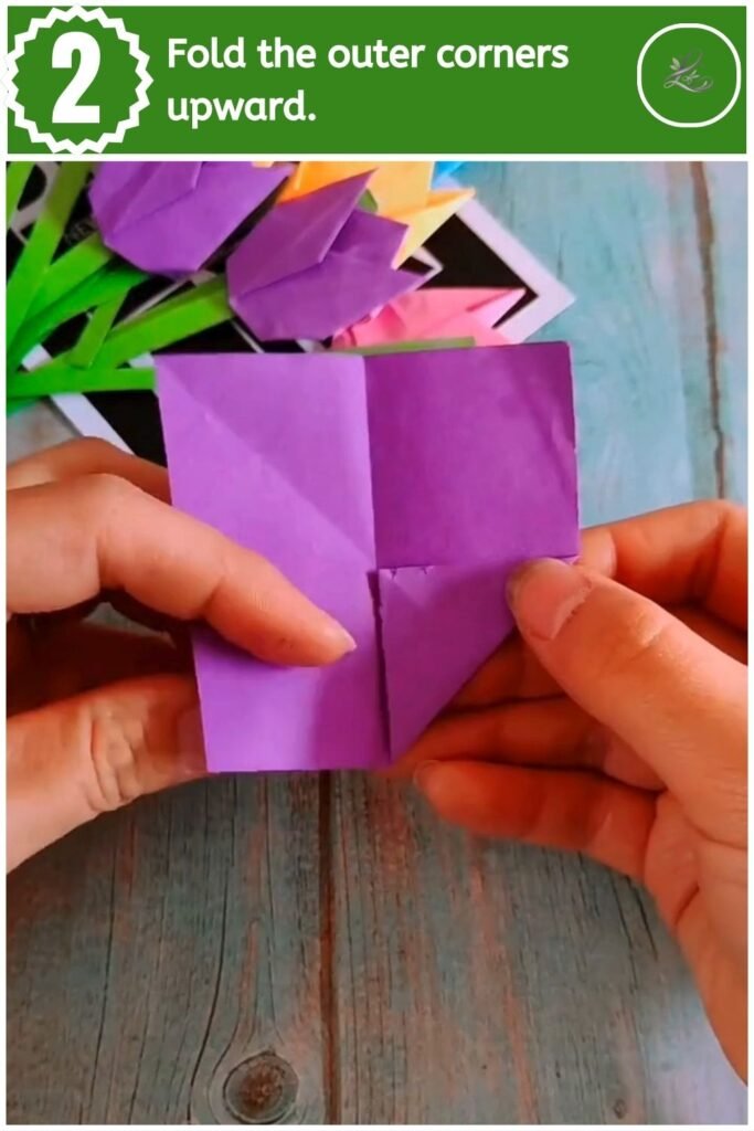 Folding the bottom corners of a paper triangle upward to shape tulip petals.