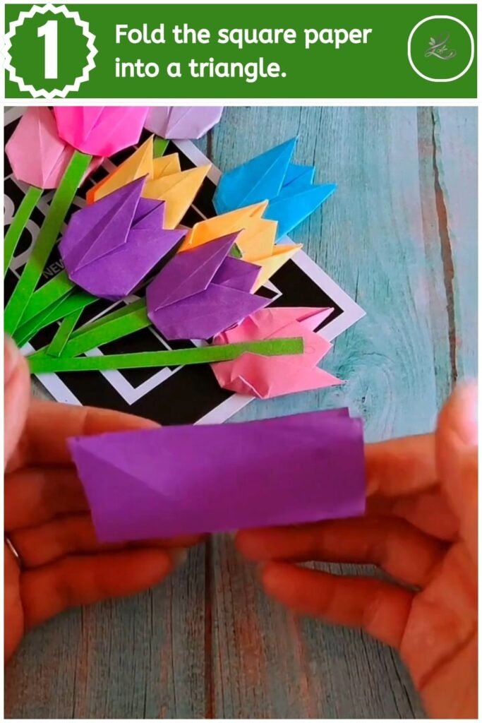 Folding a square piece of purple paper diagonally into a triangle.