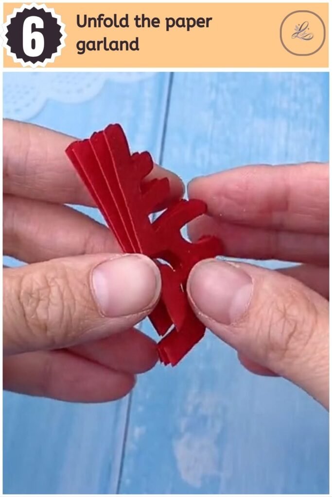 Unfolding the red paper cut craft to reveal a repeating Chinese character banner.