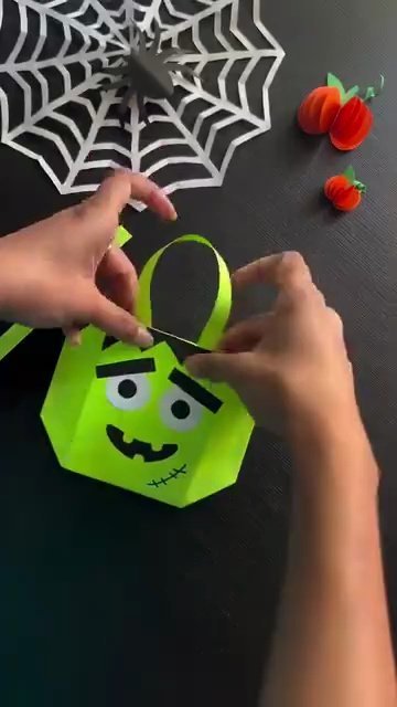 Gluing matching green paper handles to the top of the treat basket