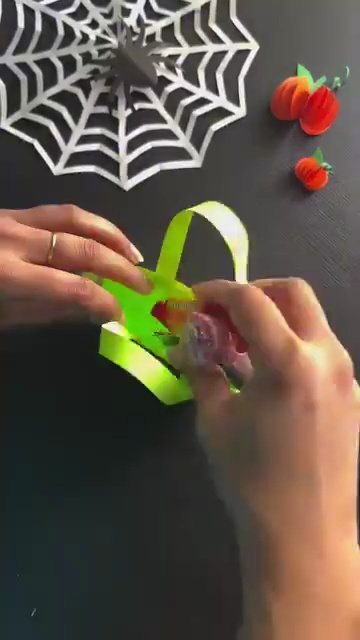 Filling green Frankenstein paper treat bag with lollipops and candy